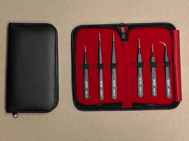 Set of ESD Safe tweezers in a red and black case on a beige background