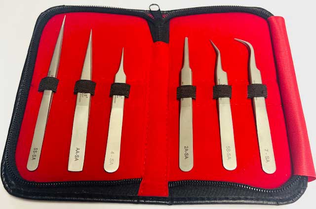 Set of six tweezers in a red case with black straps on a white background, more close up view