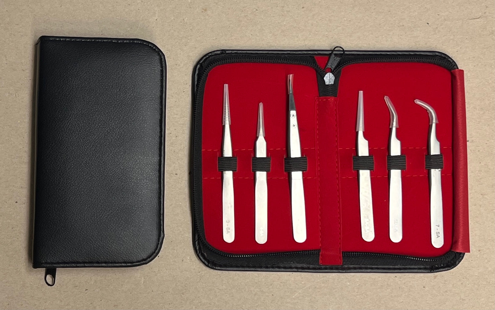 Set of stainless Steel Watchmakers weezers in a red case with a black cover on a beige background